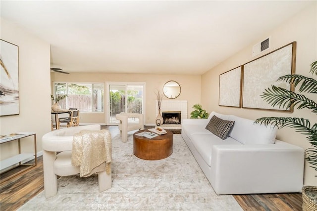 living room with visible vents, baseboards, wood finished floors, and a fireplace