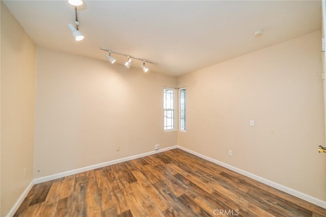 spare room featuring baseboards, wood finished floors, and track lighting