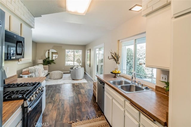 kitchen featuring dark wood-style flooring, butcher block countertops, a sink, appliances with stainless steel finishes, and open floor plan