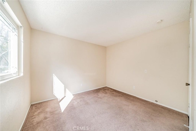 carpeted empty room featuring baseboards and a textured ceiling