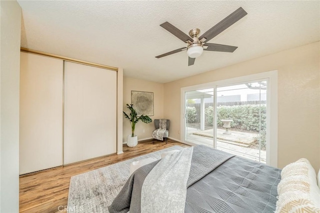 bedroom featuring a ceiling fan, wood finished floors, access to exterior, a closet, and a textured ceiling