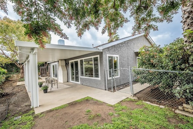 rear view of house featuring stucco siding, a patio, and fence