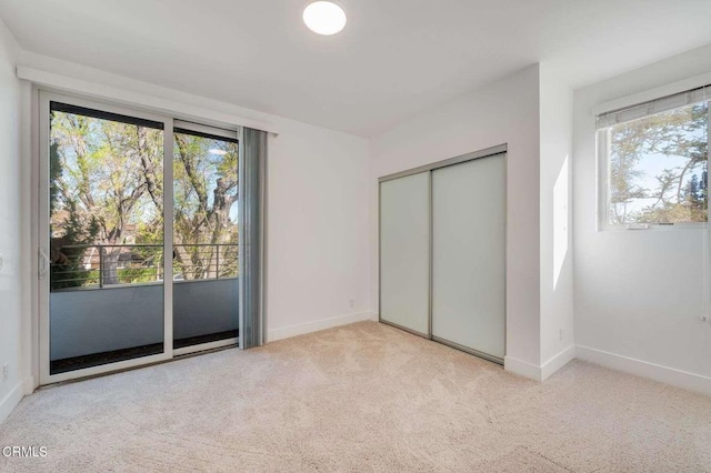 unfurnished bedroom featuring light carpet, access to outside, baseboards, and a closet