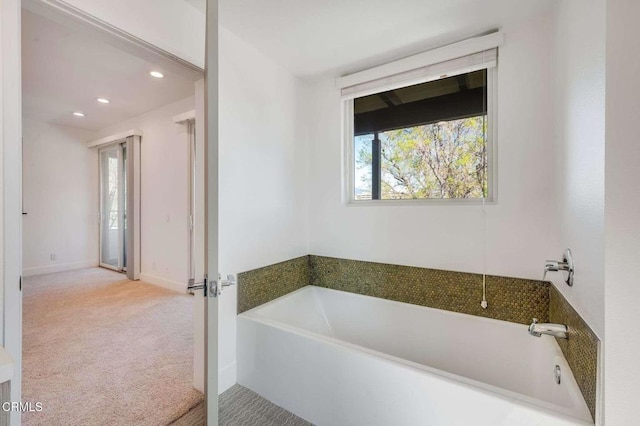 bathroom with baseboards, a bath, and recessed lighting