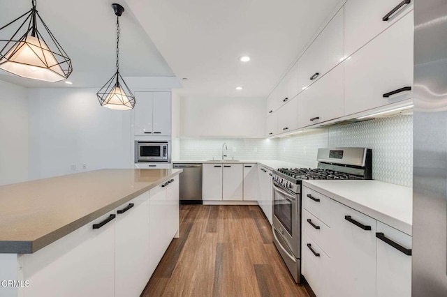 kitchen with decorative backsplash, white cabinets, dark wood finished floors, appliances with stainless steel finishes, and a sink