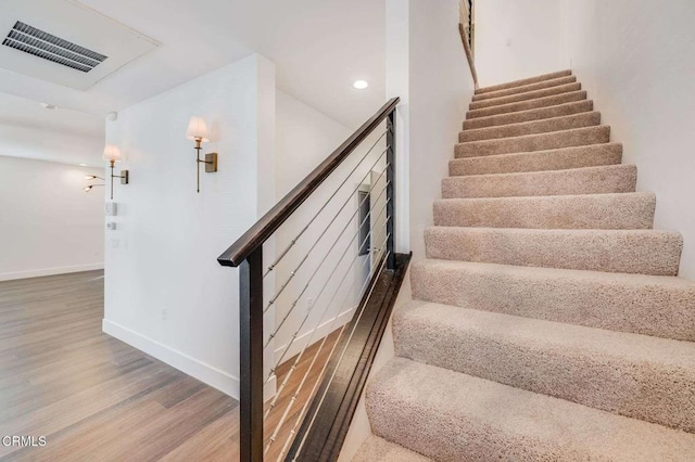 staircase featuring baseboards, visible vents, wood finished floors, and recessed lighting