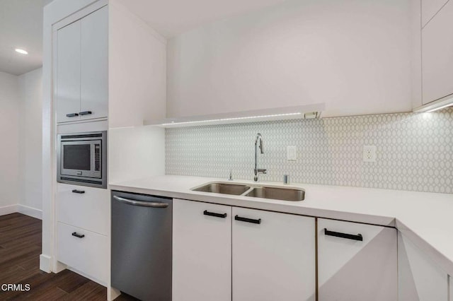 kitchen with stainless steel appliances, light countertops, a sink, and backsplash