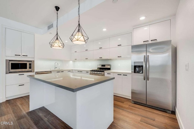 kitchen with appliances with stainless steel finishes, wood finished floors, visible vents, and white cabinets