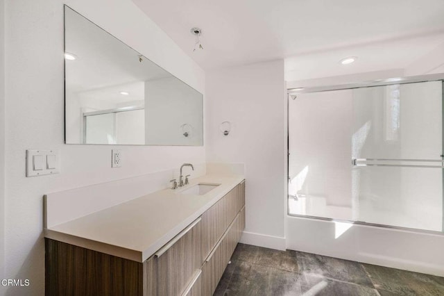 bathroom featuring combined bath / shower with glass door, vanity, and baseboards