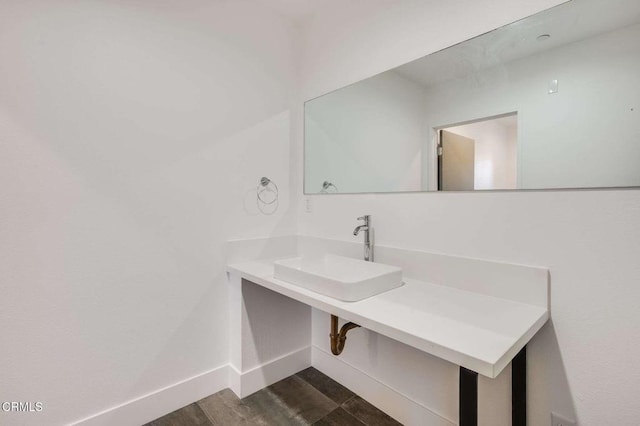 bathroom featuring wood finished floors, a sink, and baseboards