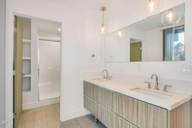 full bathroom featuring double vanity, a stall shower, baseboards, and a sink