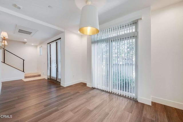 unfurnished living room featuring stairs, baseboards, visible vents, and wood finished floors