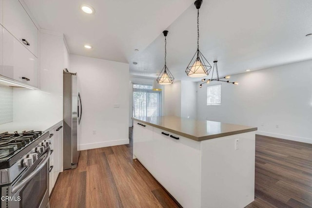 kitchen with pendant lighting, appliances with stainless steel finishes, a center island, white cabinets, and dark wood-style floors