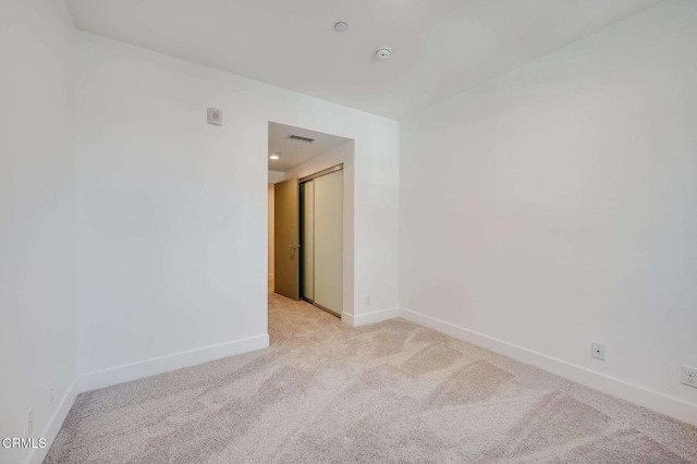 spare room with visible vents, baseboards, and light carpet