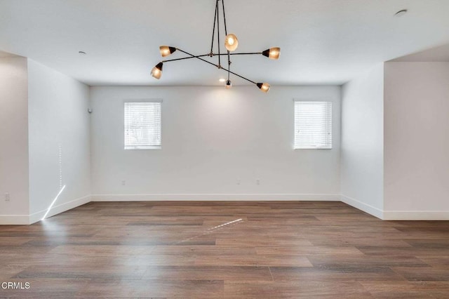 empty room with baseboards, plenty of natural light, and a chandelier