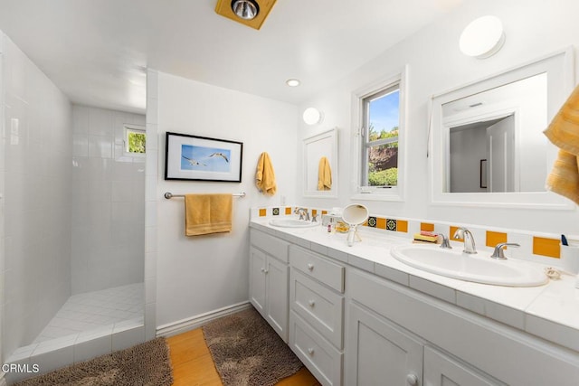 full bathroom featuring a sink, wood finished floors, double vanity, and a walk in shower