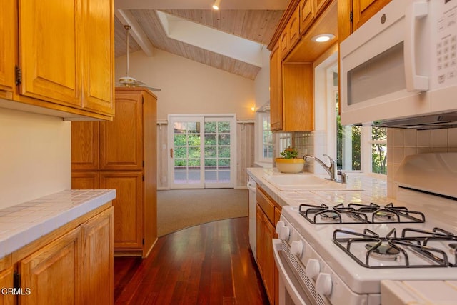 kitchen featuring a healthy amount of sunlight, tile counters, beam ceiling, white appliances, and a sink