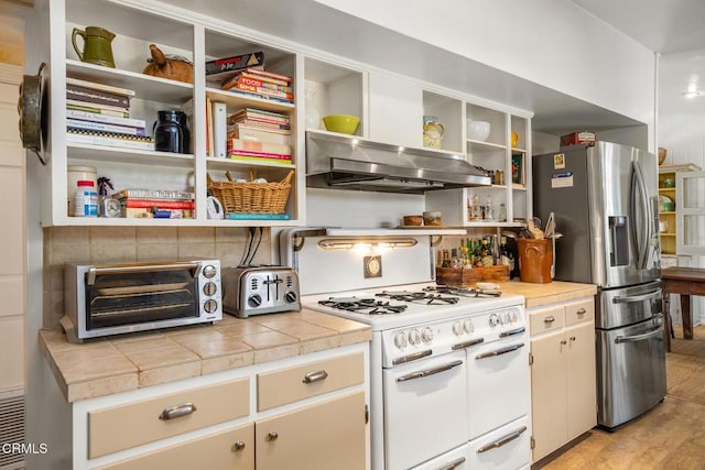 kitchen featuring open shelves, double oven range, stainless steel refrigerator with ice dispenser, and extractor fan