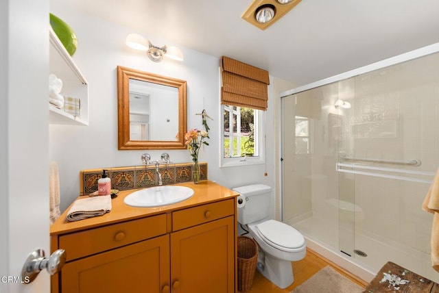 bathroom featuring toilet, a stall shower, and vanity