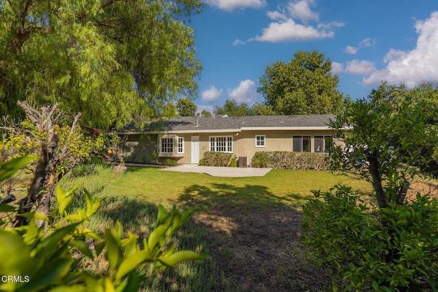 back of house with a lawn and stucco siding