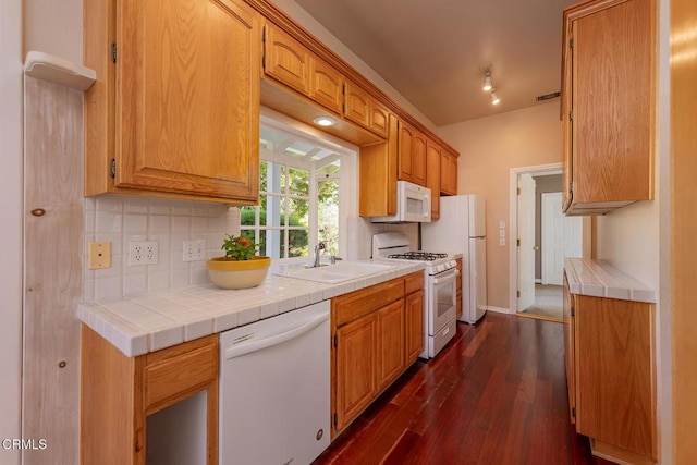 kitchen featuring dark wood-type flooring, a sink, tasteful backsplash, tile countertops, and white appliances