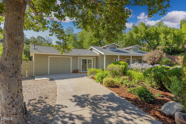 view of front facade featuring driveway, an attached garage, and fence