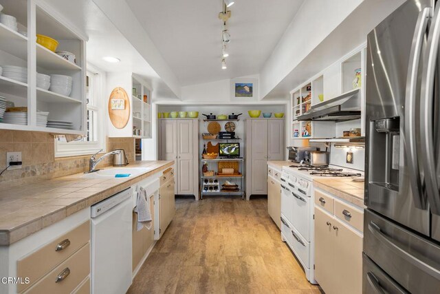 kitchen featuring tile countertops, vaulted ceiling, decorative backsplash, white appliances, and open shelves