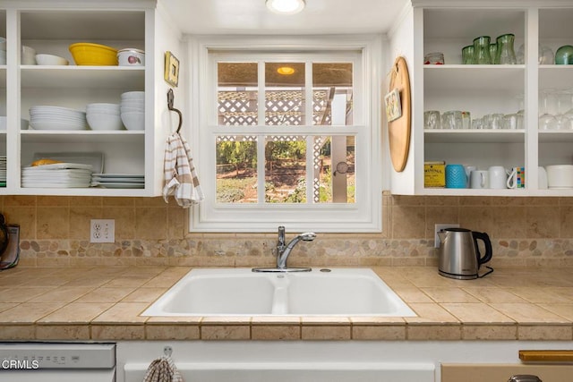 kitchen with a sink, open shelves, dishwasher, and tile counters