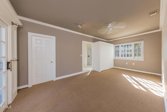 unfurnished bedroom featuring baseboards, visible vents, carpet floors, and ornamental molding