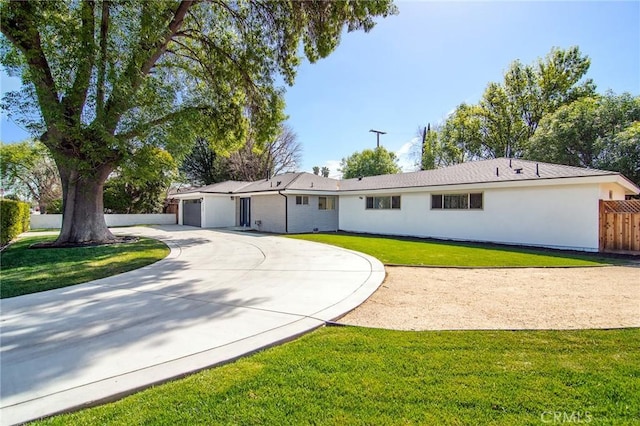 single story home featuring a front yard, curved driveway, fence, and stucco siding