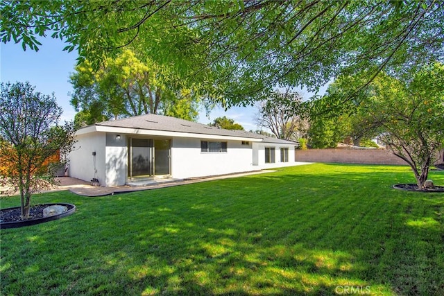 back of house featuring stucco siding, a patio, and a yard