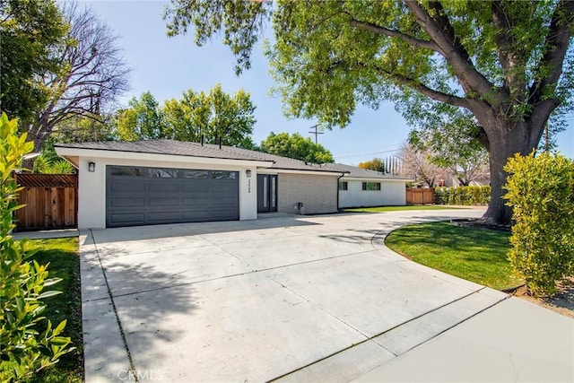 single story home with concrete driveway, fence, an attached garage, and stucco siding