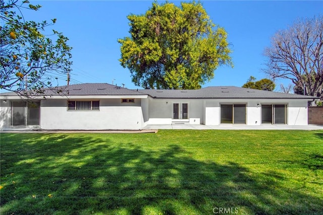 back of house with stucco siding, a yard, a patio, and french doors