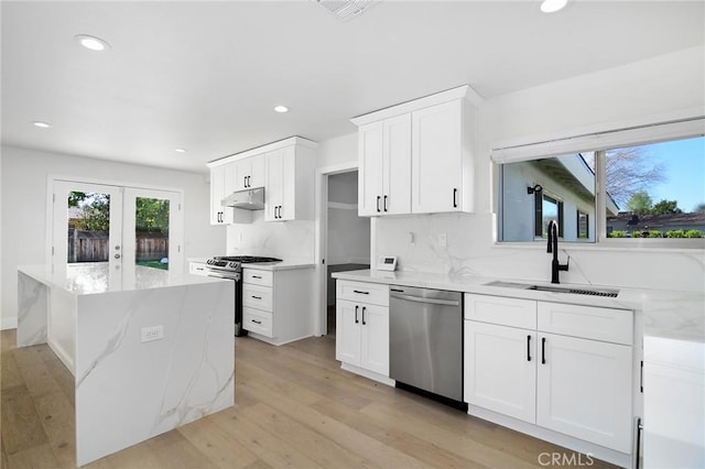 kitchen featuring french doors, appliances with stainless steel finishes, light wood-style floors, a sink, and under cabinet range hood