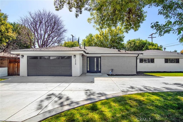 ranch-style home featuring stucco siding, concrete driveway, a front yard, fence, and a garage