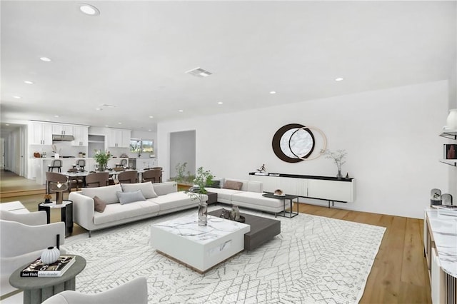 living room with light wood-type flooring, visible vents, and recessed lighting