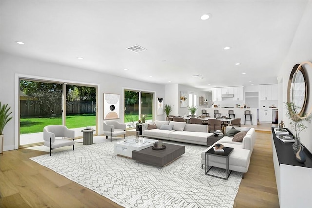 living area featuring light wood-type flooring, visible vents, and recessed lighting