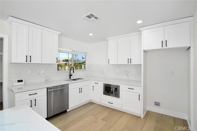 kitchen with visible vents, dishwasher, built in microwave, light wood-type flooring, and a sink