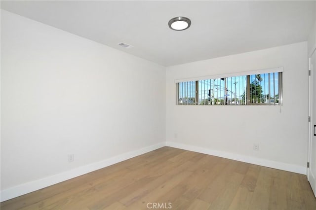 empty room featuring visible vents, baseboards, and wood finished floors