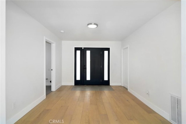 foyer with light wood-type flooring, baseboards, and visible vents