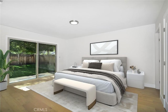 bedroom featuring access to exterior, baseboards, and wood finished floors