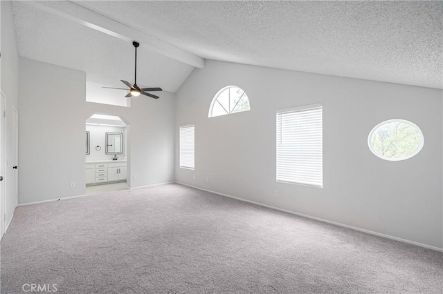 unfurnished living room with arched walkways, ceiling fan, beamed ceiling, carpet, and high vaulted ceiling