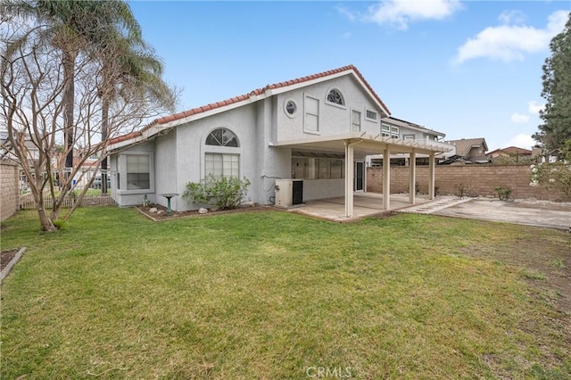 rear view of property featuring a patio area, fence, a lawn, and stucco siding