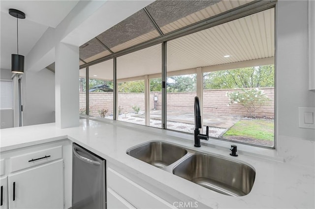 kitchen featuring stainless steel dishwasher, a sink, a wealth of natural light, and white cabinets