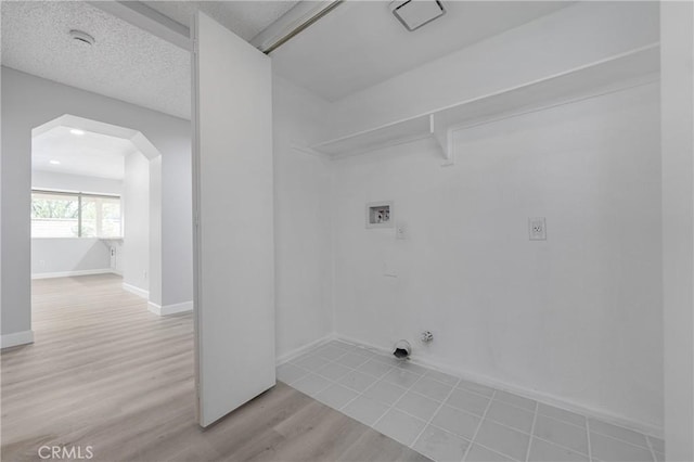 clothes washing area featuring arched walkways, hookup for a gas dryer, a textured ceiling, wood finished floors, and laundry area