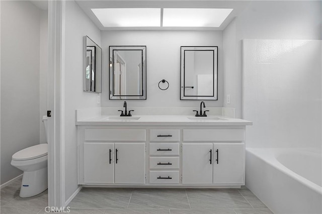 bathroom featuring toilet, double vanity, and a sink