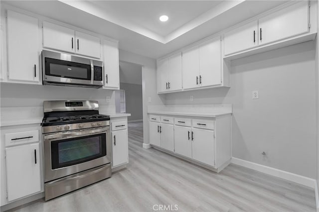 kitchen featuring stainless steel appliances, light countertops, white cabinetry, and baseboards