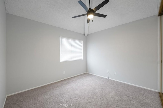 spare room featuring baseboards, a ceiling fan, carpet, vaulted ceiling, and a textured ceiling