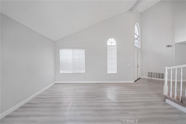 unfurnished room with beam ceiling, light wood-type flooring, visible vents, and baseboards