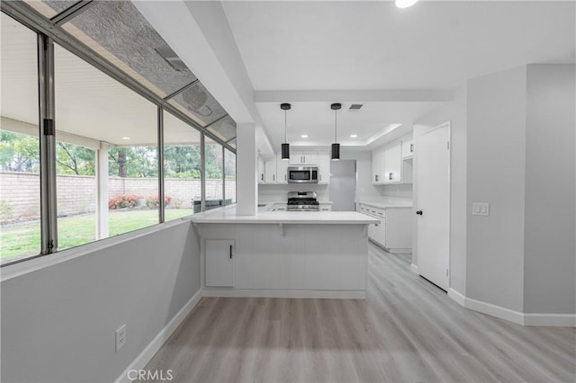 kitchen with stainless steel appliances, a peninsula, white cabinetry, baseboards, and light wood-style floors